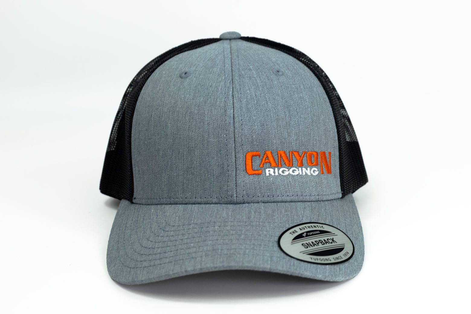 Canyon Rigging product photos of our rigging snap back cap. The hat is a grey with Canyon Rigging's logo on it. the back of the hat is mesh with a snap size adjuster. This is a photo of the front of the hat.